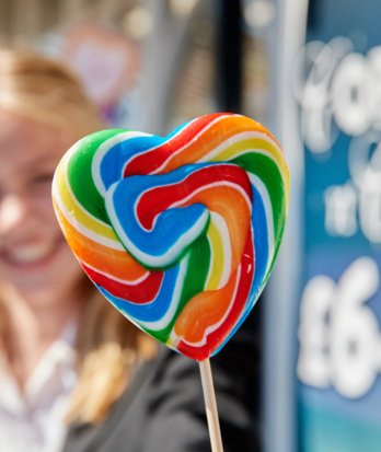 Smiling pupil holding a rainbow heart lollipop on the Pier