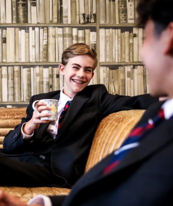 Boarding pupils sitting in their Common Room talking to each other whilst drinking a cup of tea