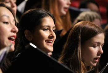  Chamber choir singing a piece holding their music in a concert 