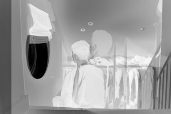  X-ray style photograph of a person sitting on the stairs looking through a window with clothes rail at the bottom of the stairs 