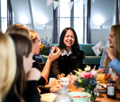  Boarders with toast and tea enjoying talking around a table in the Common Room 