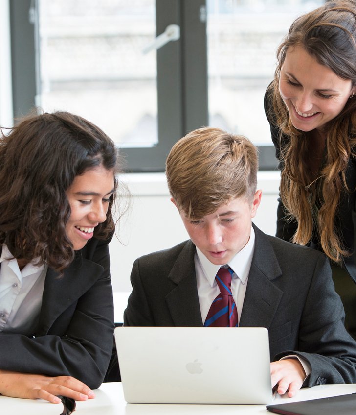  Pupils and their teacher looking at something on a laptop in a lesson 
