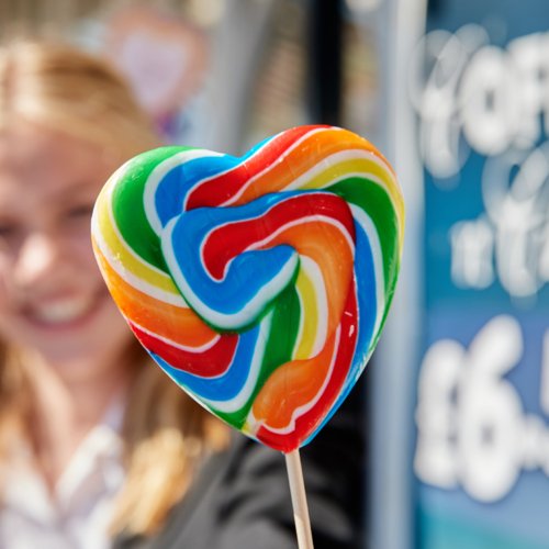 Smiling pupil holding a rainbow heart lollipop on the Pier 