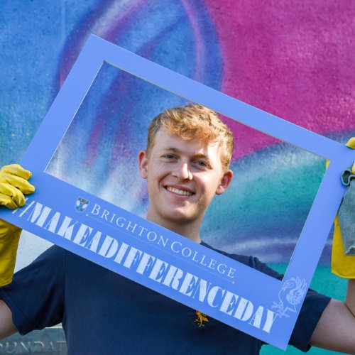  Pupil happily holding a Brighton College #MakeADifferenceDay sign 
