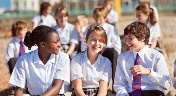  Lower School pupils sitting on the beach and enjoying talking to each other 