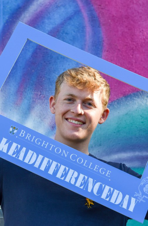  Pupil happily holding a Brighton College #MakeADifferenceDay sign 